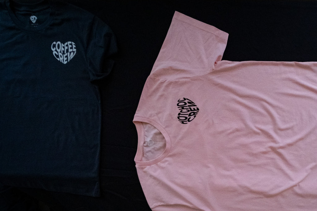 Black t-shirt with 'Coffee Crew' logo and pink t-shirt with similar logo on a black background