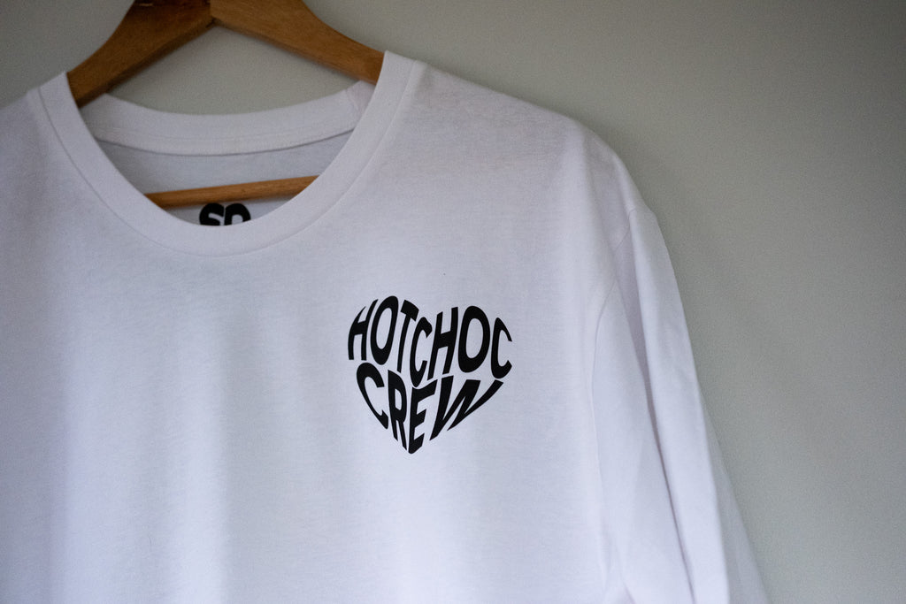 White sweatshirt with 'Hotchoc Crew' text on a hanger against a plain background