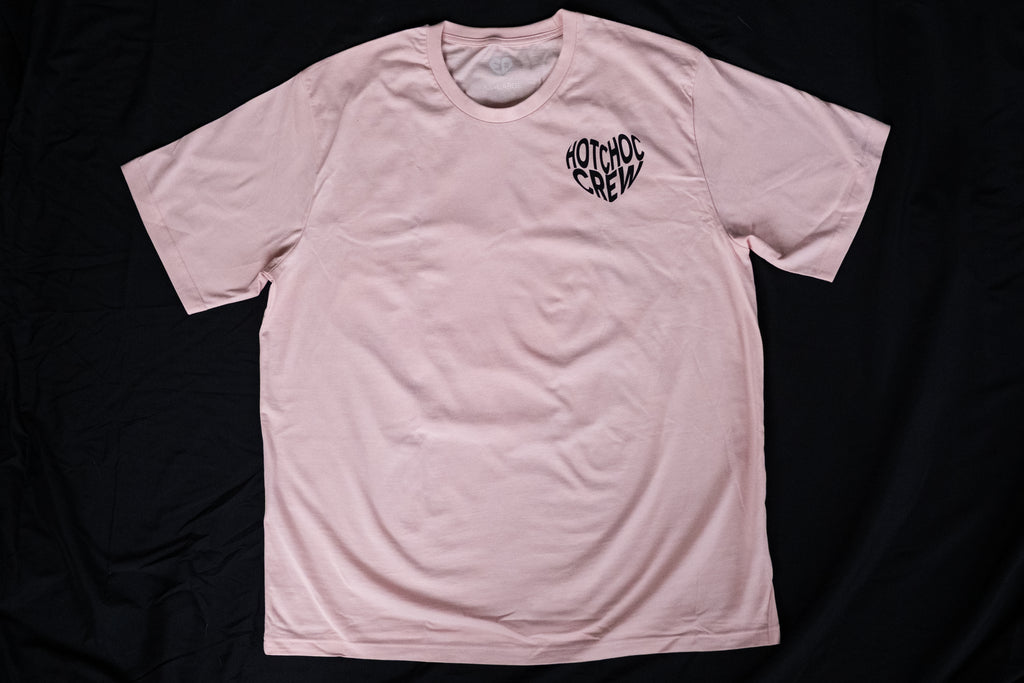 Pink t-shirt with a black logo on a black background